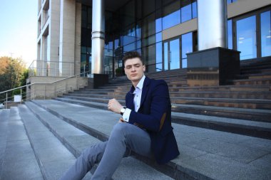 Yakışıklı işadamı Merdiven yapı üzerinde oturan  