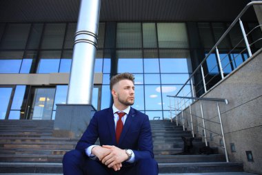 Yakışıklı işadamı Merdiven yapı üzerinde oturan  