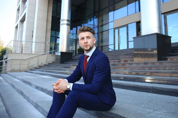 Yakışıklı işadamı Merdiven yapı üzerinde oturan  