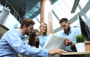 Group of young modern people in smart casual wear having a brainstorm meeting while standing in the creative office. clipart