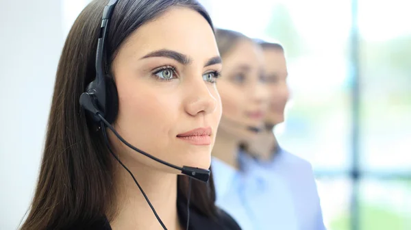 Portret van callcenter medewerker vergezeld door haar team. Lachende klant support operator aan het werk. — Stockfoto