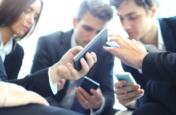 Groupe de personnes utilisant des téléphones intelligents assis à la réunion, gros plan sur les mains . — Photo