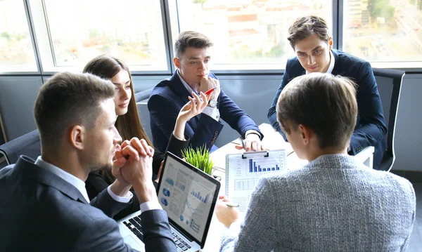 Brainstorming. Groupe de gens d'affaires regardant l'ordinateur portable ensemble. Une femme d'affaires regardant la caméra . — Photo