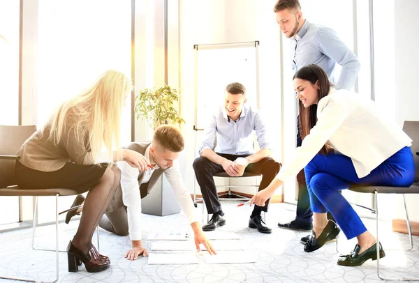 Personas creativas mirando el plan de proyecto dispuesto en el piso. Socios de negocios discuten plan de proyecto en oficina moderna . —  Fotos de Stock