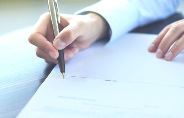 Бизнесмен, сидящая за рабочим столом, подписывает контракт с мелким акцентом на подпись
.