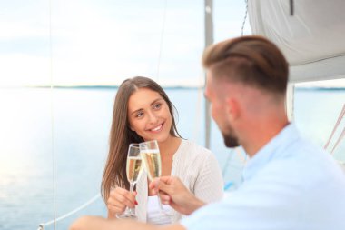 Şampanya ile genç çift gülümseyen ve birbirine yat gemide otururken bakarak.