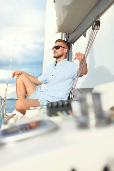 Relaxing man sitting on boat sailing on sea happy and carefree. Stock Picture