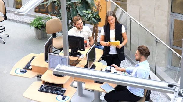 Visão superior de jovens colegas modernos em desgaste casual inteligente trabalhando juntos enquanto passam tempo no escritório . — Fotografia de Stock