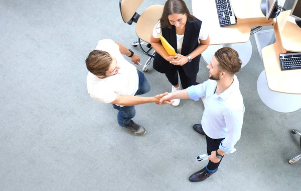 Bovenaanzicht van jonge zakenpartners schudden handen over deal op kantoor. Focus op de hand schudden. — Stockfoto