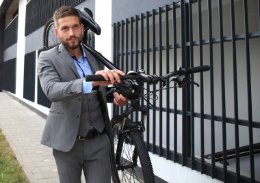 Kendine güvenen genç işadamı açık havada yürürken onun bisiklet taşıma.