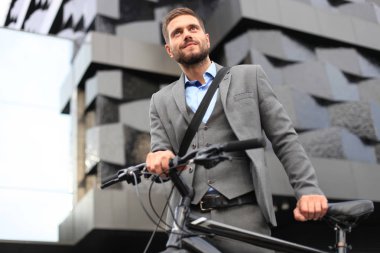 Kendine güvenen genç işadamı bisiklet ile şehirde sokakta yürüme.