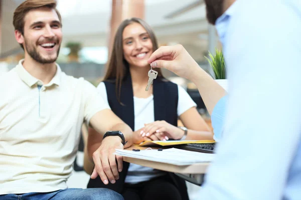 Närbild på fastighetsmäklare ger nycklar till par kunder. — Stockfoto