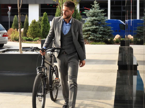 Jovem empresário confiante andando de bicicleta na rua da cidade . — Fotografia de Stock