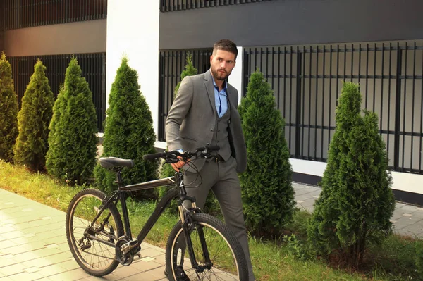 Уверенный молодой бизнесмен, гуляющий на велосипеде по улице в городе . — стоковое фото