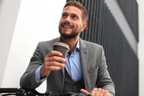Zeker jonge zakenman met zijn fiets buiten koffie drinken. — Stockfoto