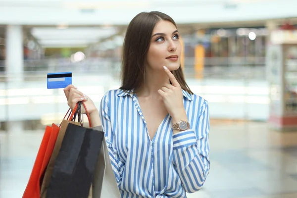 Shopper fille tenant la carte de crédit et sacs à provisions levant les yeux . — Photo