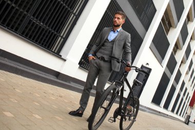 Kendine güvenen genç işadamı bisiklet ile şehirde sokakta yürüme.