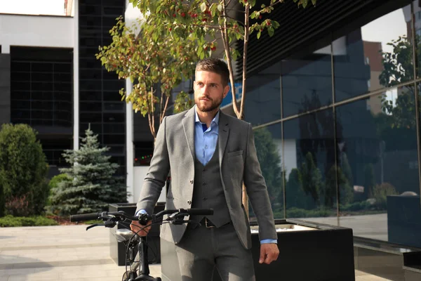 Jovem empresário confiante andando de bicicleta na rua da cidade . — Fotografia de Stock