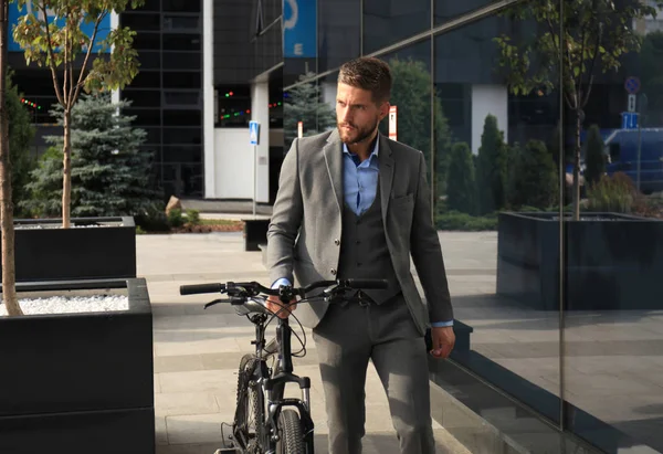 Jovem empresário confiante andando de bicicleta na rua da cidade . — Fotografia de Stock