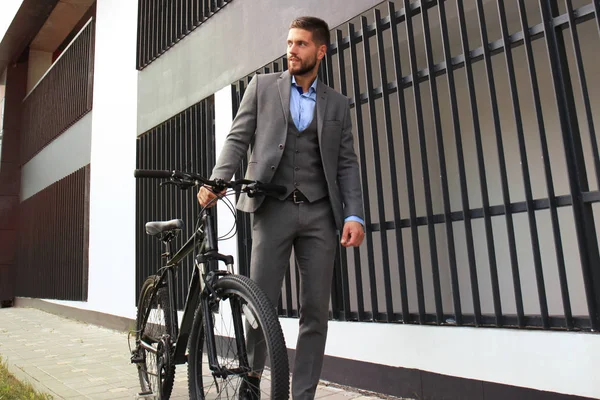 Selbstbewusster junger Geschäftsmann läuft mit Fahrrad auf der Straße in der Stadt. — Stockfoto