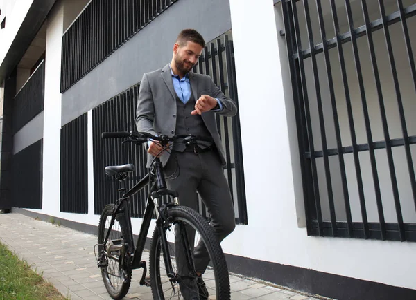 Retrato do jovem empresário com sua bicicleta olhando para o relógio . — Fotografia de Stock
