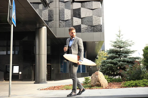 Zeker jonge zakenman lopen op de straat, met behulp van longboard. — Stockfoto