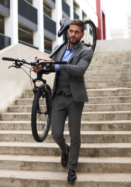 Αυτοπεποίθηση νεαρός επιχειρηματίας που μεταφέρουν το ποδήλατό του, ενώ το περπάτημα σε εξωτερικούς χώρους. — Φωτογραφία Αρχείου