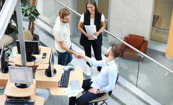 Ovanifrån av unga affärspartners som skakar hand över affär på kontoret. Fokusera å skaka. — Stockfoto