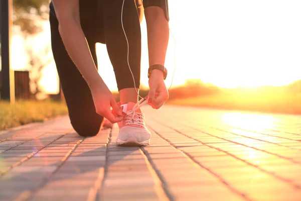 Junge Fitness attraktive sportliche Läuferin schnürt die Schnürsenkel an ihren Sportschuhen und macht sich bereit zum Laufen. — Stockfoto