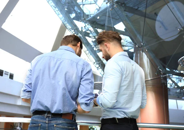 Groupe de jeunes gens modernes en tenue décontractée intelligente ayant une réunion de remue-méninges tout en se tenant dans le bureau créatif . — Photo