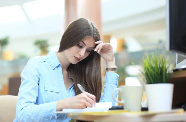 Junge Frau am Arbeitsplatz blättert in Tagebuchnotizen. — Stockfoto