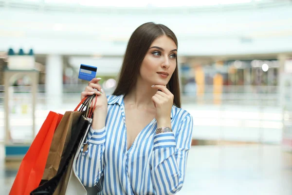 Shopper menina segurando cartão de crédito e sacos de compras olhando para cima . — Fotografia de Stock