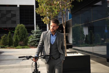 Kendine güvenen genç işadamı bisiklet ile şehirde sokakta yürüme.