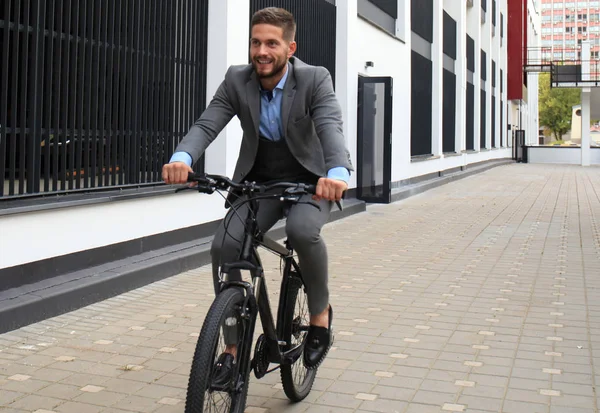 Bonito jovem empresário andar de bicicleta ao ar livre na cidade . — Fotografia de Stock