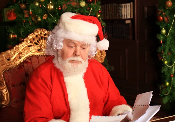 Père Noël assis au sapin de Noël, tenant des lettres de Noël et se reposant près de la cheminée . — Photo