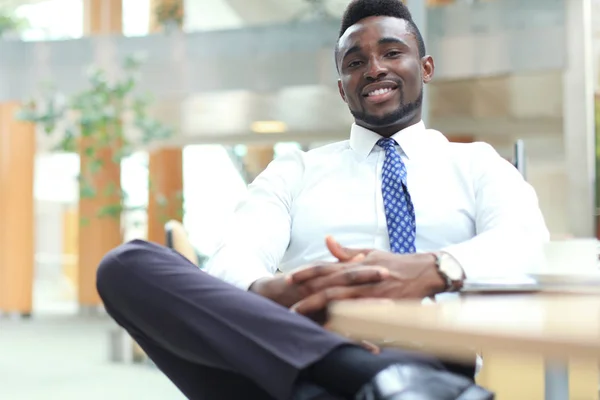 Feliz joven empresario afroamericano mirando la cámara en el lugar de trabajo en la oficina . —  Fotos de Stock