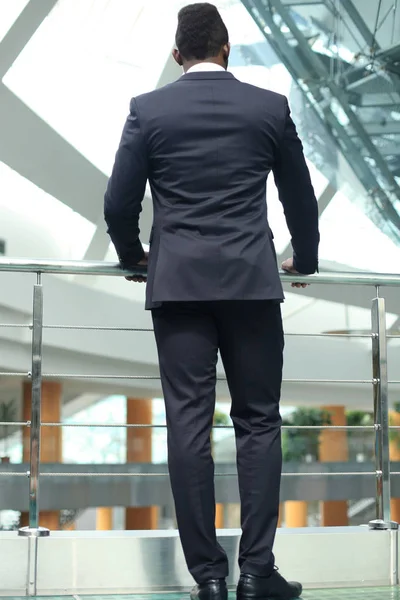 Vue arrière d'un homme d'affaires afro-américain en costume tourné vers l'avenir, dans un immeuble de bureaux . — Photo