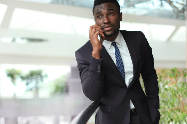 Exitoso guapo hombre de negocios afroamericano hablando por teléfono móvil en la oficina moderna . —  Fotos de Stock