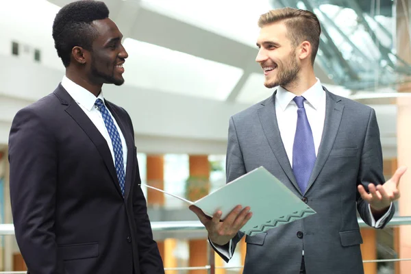 オフィスでの会議でビジネスを議論する 2 つの多国籍若手ビジネスマン. — ストック写真