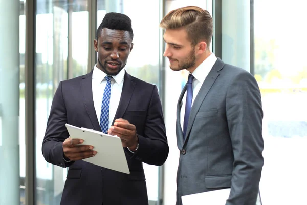 Два многонациональных молодых бизнесмена обсуждают бизнес на встрече в офисе . — стоковое фото