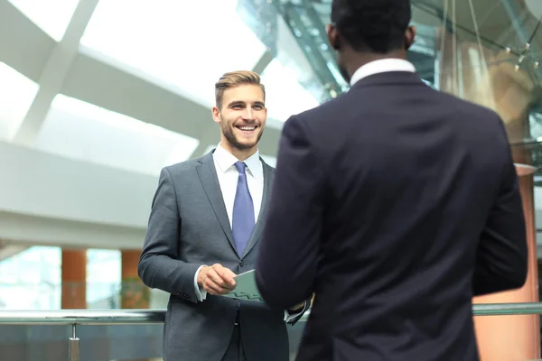 Twee multinationale jonge ondernemers bespreken van zaken tijdens de bijeenkomst in kantoor. — Stockfoto