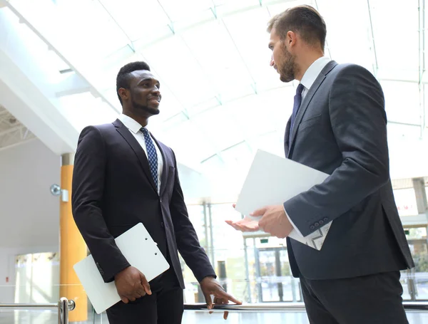 Två multinationella unga affärsmän diskuterar verksamheten vid möte i office. — Stockfoto