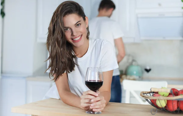 Bella giovane donna che beve del vino a casa in cucina . — Foto Stock