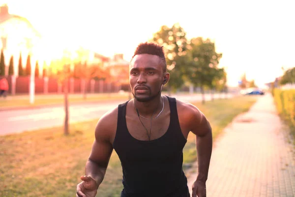 Hombre africano con ropa deportiva corriendo mientras hace ejercicio al aire libre, al atardecer o al amanecer. Corredor . —  Fotos de Stock