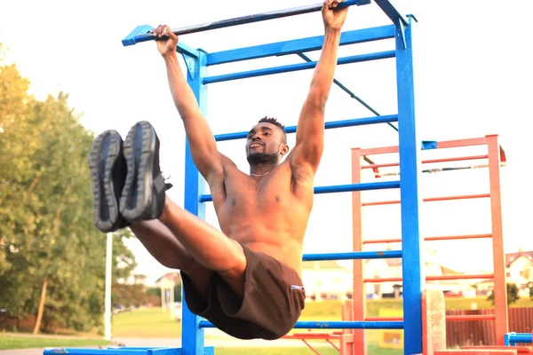 African man doing street workout on the beach, at sunset or sunrise.