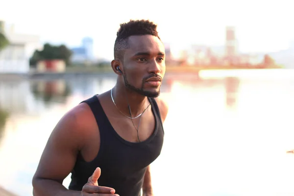 Hombre africano con ropa deportiva corriendo mientras hace ejercicio, en el retrato al aire libre de la playa, al atardecer o al amanecer. Corredor . —  Fotos de Stock