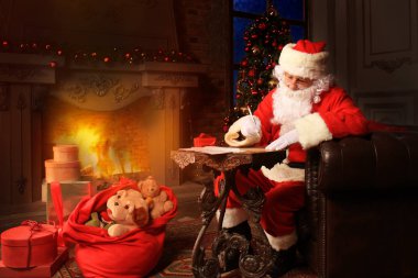 Mutlu Noel Baba 'nın portresi Noel ağacının yanındaki odasında oturuyor ve Noel mektuplarına cevap veriyor..