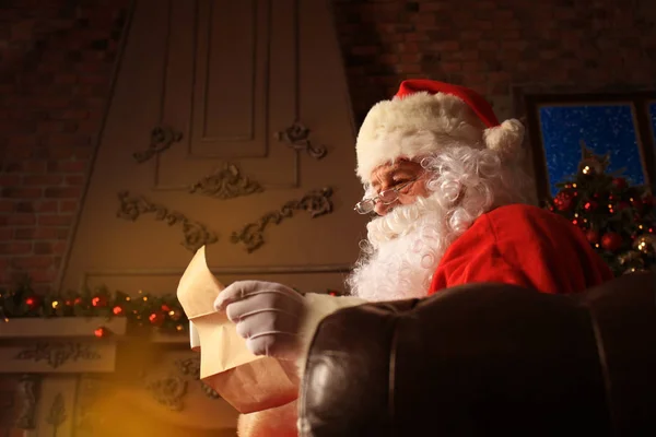 Retrato de Papai Noel feliz sentado em seu quarto em casa perto da árvore de Natal e lendo carta de Natal ou lista de desejos. — Fotografia de Stock