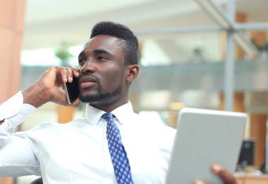 Tablet bilgisayar kullanarak ve telefonda konuşurken başarılı bir Afrikalı-Amerikalı girişimci.