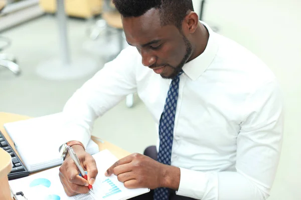 Retrato de um empresário afro-americano bem-sucedido sentado à mesa com computador no escritório . — Fotografia de Stock